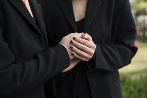 Dos personas vestidas de negro dnadose la mano