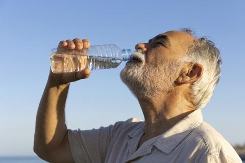 Señor mayor bebiendo agua en verano