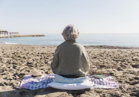 Anciana sentada en la playa mirando al mar